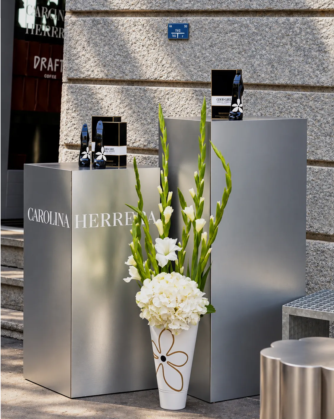 carolina-herrera-good-girl-presentoirs-parfums-converti-depuis-jpg Présentoirs argentés Carolina Herrera mettant en valeur les parfums Good Girl en forme d’escarpin, accompagnés d’une composition florale blanche.